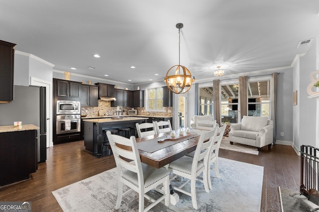 dining space with baseboards, visible vents, ornamental molding, dark wood-type flooring, and a chandelier