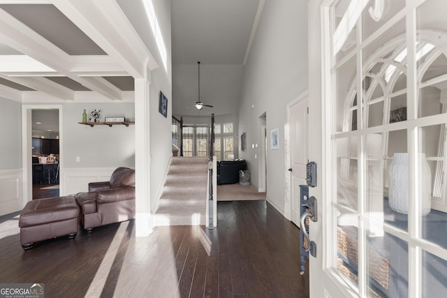 entrance foyer with a ceiling fan, dark wood-style floors, stairs, wainscoting, and beamed ceiling