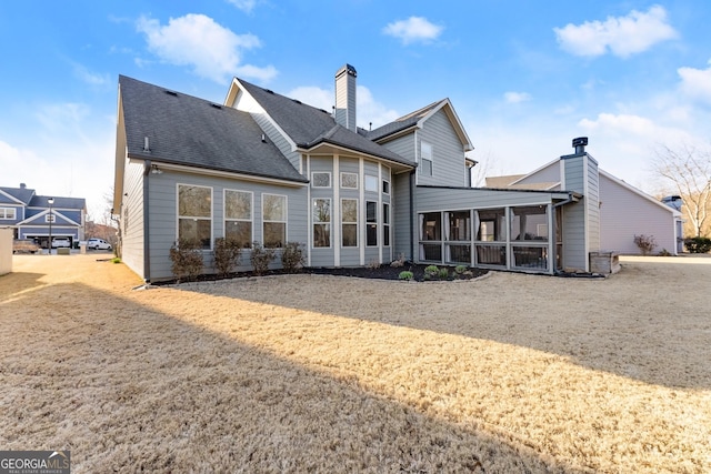 rear view of property featuring a chimney, roof with shingles, and a sunroom