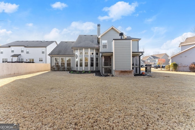 back of house featuring a yard, fence, a residential view, and a sunroom