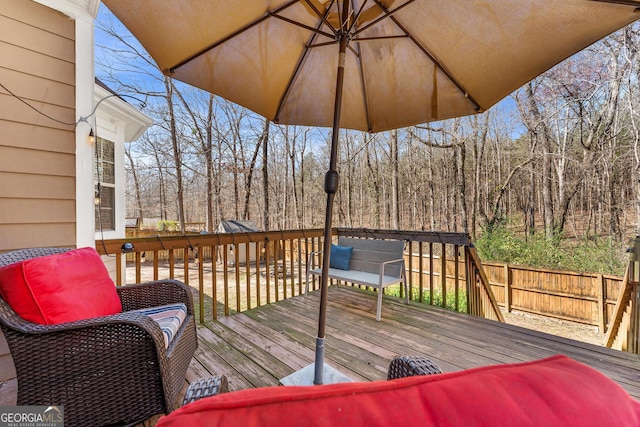 wooden terrace featuring a view of trees and fence