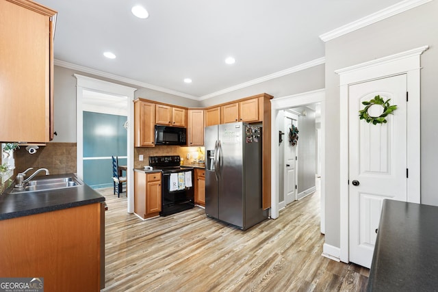 kitchen featuring tasteful backsplash, crown molding, light wood-type flooring, black appliances, and a sink