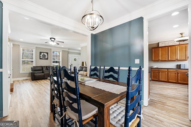 dining room featuring light wood-style flooring, ceiling fan with notable chandelier, baseboards, and ornamental molding