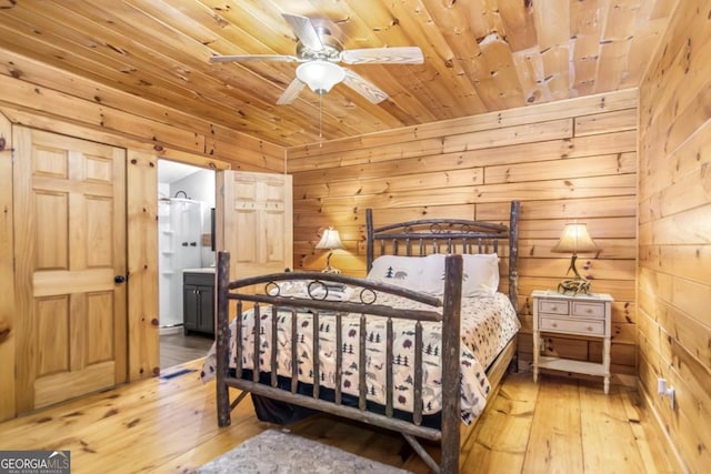 bedroom featuring hardwood / wood-style flooring, wood walls, wooden ceiling, and connected bathroom