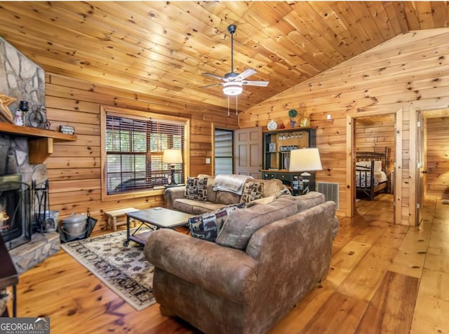 living area with wood-type flooring, wooden walls, ceiling fan, and vaulted ceiling