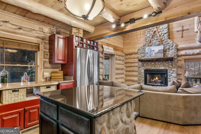 kitchen with beamed ceiling, wood ceiling, freestanding refrigerator, rustic walls, and reddish brown cabinets