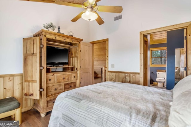 bedroom featuring visible vents, wood finished floors, wooden walls, and a wainscoted wall