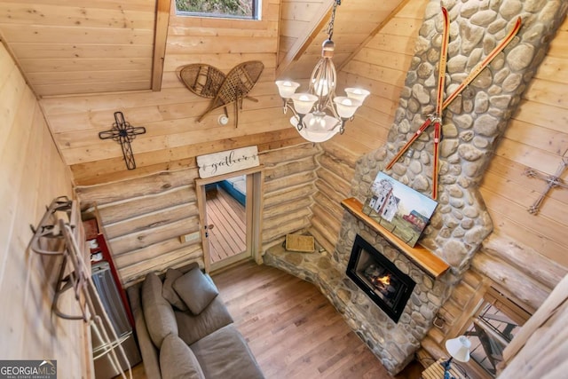 living room featuring wood finished floors, an inviting chandelier, wooden ceiling, a fireplace, and log walls