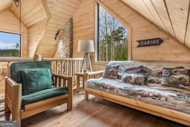 living area featuring lofted ceiling, wood finished floors, wood walls, and wooden ceiling