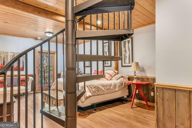 bedroom featuring wainscoting, wooden ceiling, and wood finished floors