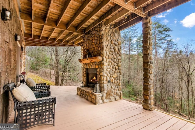 wooden terrace with an outdoor stone fireplace