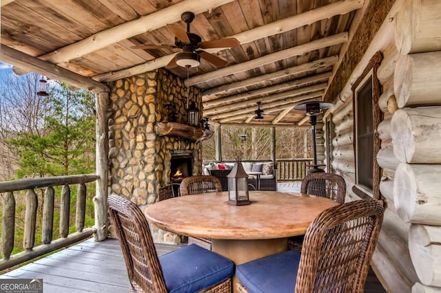 wooden terrace featuring a ceiling fan and an outdoor stone fireplace