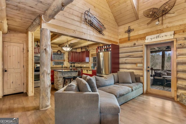 living area featuring log walls, wood finished floors, beam ceiling, and wooden ceiling