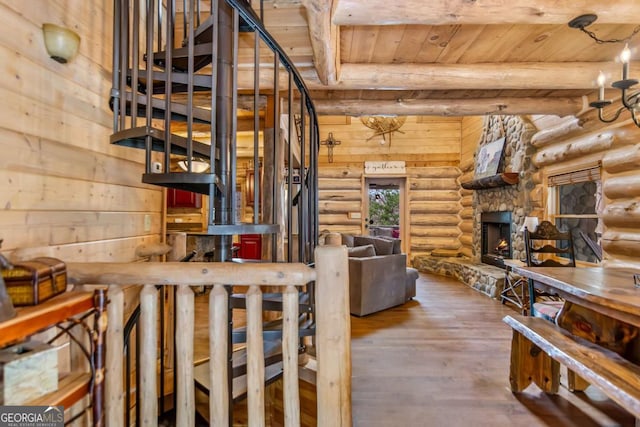 interior space featuring beamed ceiling, wooden ceiling, a fireplace, wood finished floors, and rustic walls