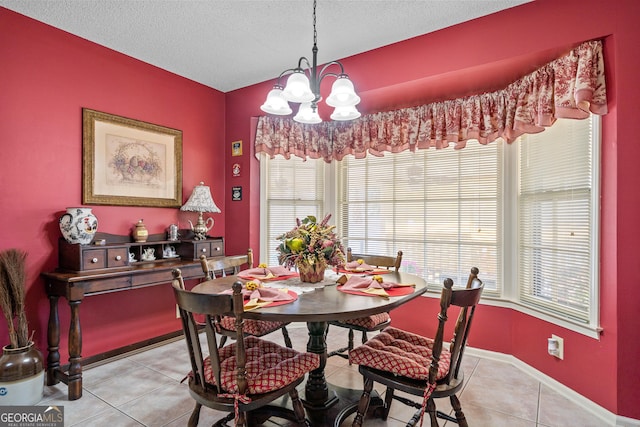 dining space featuring a textured ceiling, light tile patterned floors, baseboards, and a chandelier