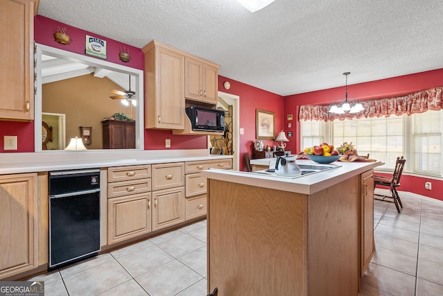 kitchen with black microwave, a textured ceiling, light brown cabinets, and light countertops