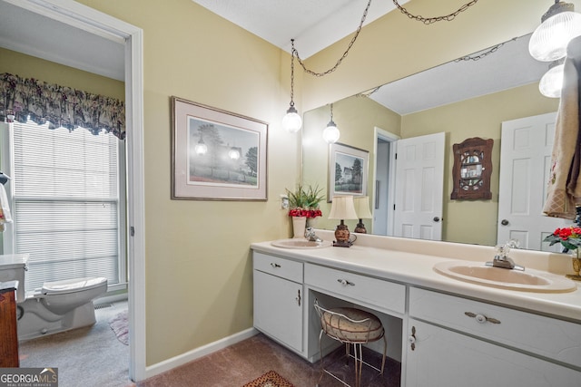 bathroom with double vanity, toilet, baseboards, and a sink