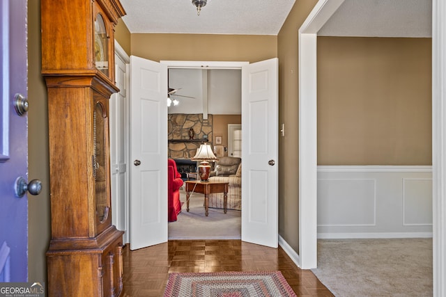 entryway with a decorative wall, a fireplace, a wainscoted wall, and a textured ceiling