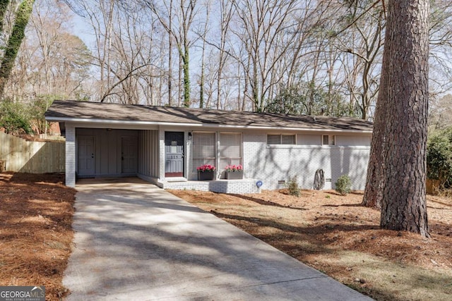 view of front facade featuring crawl space, brick siding, driveway, and fence