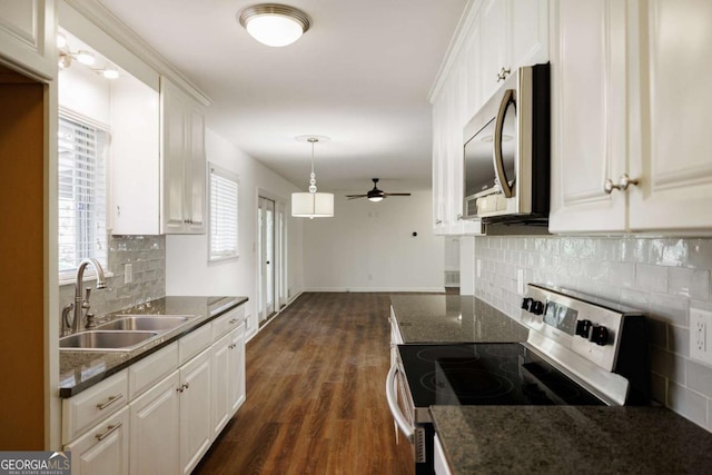 kitchen featuring ceiling fan, dark wood finished floors, appliances with stainless steel finishes, white cabinets, and a sink