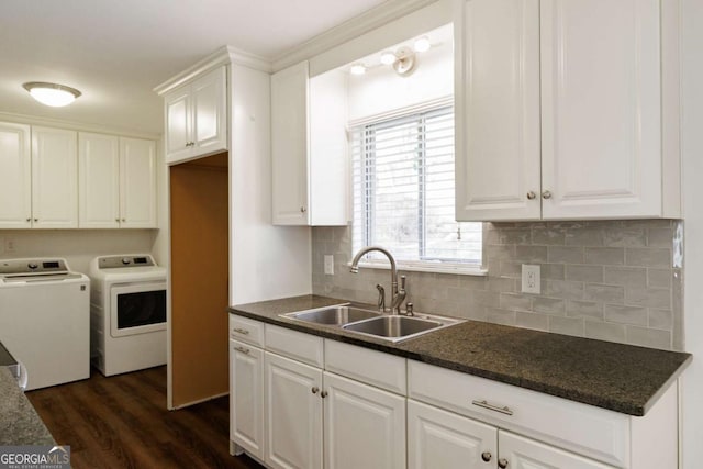 kitchen featuring dark wood-style floors, a sink, decorative backsplash, white cabinets, and washer and dryer