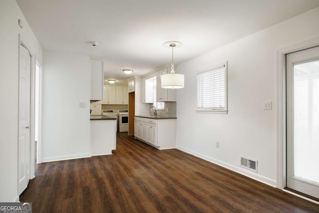 kitchen with dark countertops, white cabinets, baseboards, and visible vents