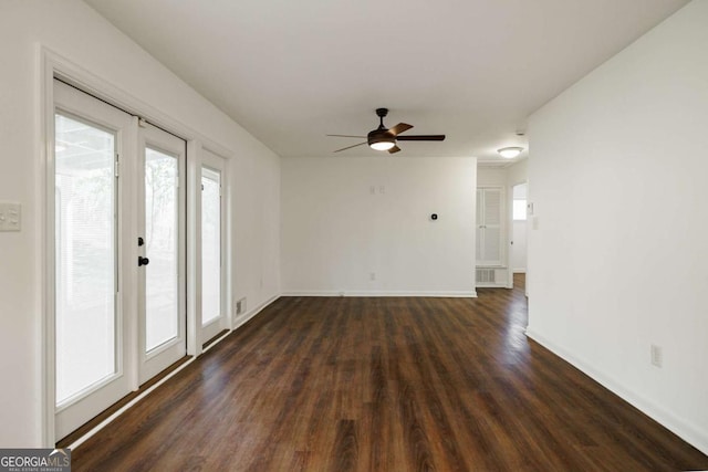 unfurnished room with a ceiling fan, visible vents, dark wood-style floors, and baseboards