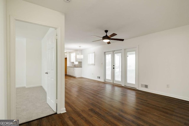 unfurnished living room featuring dark wood finished floors, baseboards, visible vents, and ceiling fan