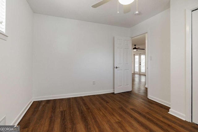 empty room with ceiling fan, baseboards, and dark wood finished floors