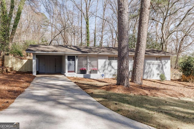 view of front of house with crawl space, concrete driveway, brick siding, and fence