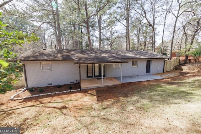 rear view of house featuring crawl space, a patio area, brick siding, and fence