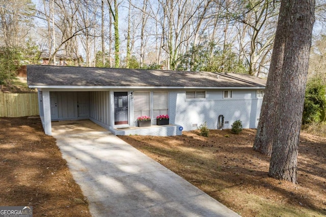 view of front of home with a carport, fence, concrete driveway, crawl space, and brick siding