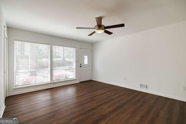 unfurnished room with visible vents, ceiling fan, dark wood-type flooring, and baseboards