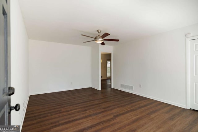 spare room featuring dark wood-style floors, visible vents, and baseboards