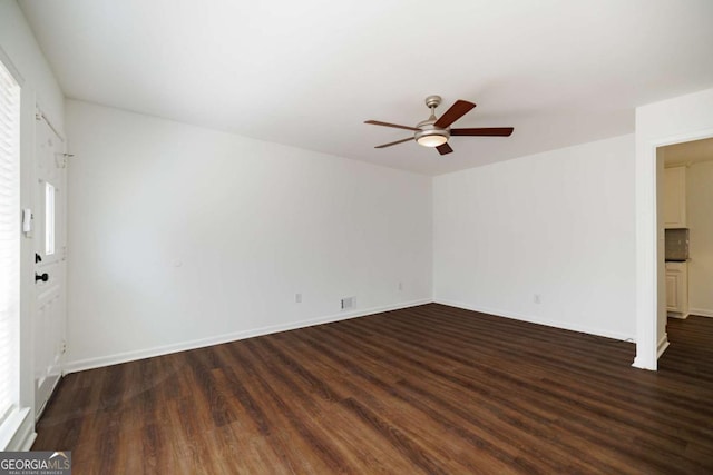 empty room featuring dark wood-style floors, baseboards, and ceiling fan