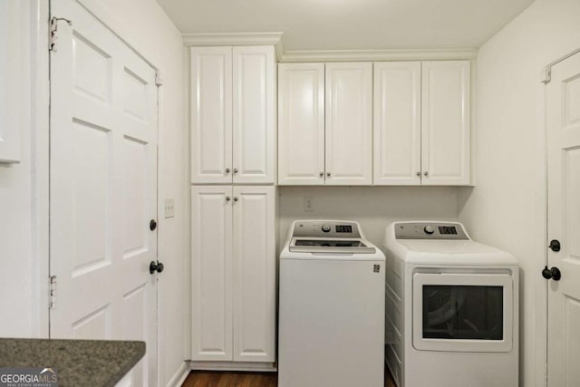 washroom with dark wood finished floors, cabinet space, and washing machine and dryer