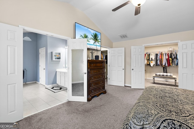 carpeted bedroom with tile patterned floors, visible vents, a walk in closet, a ceiling fan, and lofted ceiling