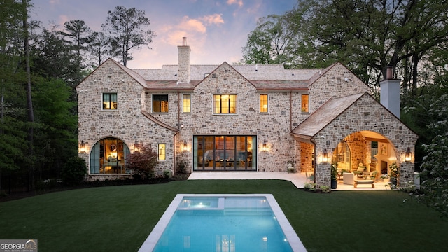41 Blackland Rd NW, Atlanta, GA 30342 - back of property at dusk featuring a chimney, a patio, and a lawn
