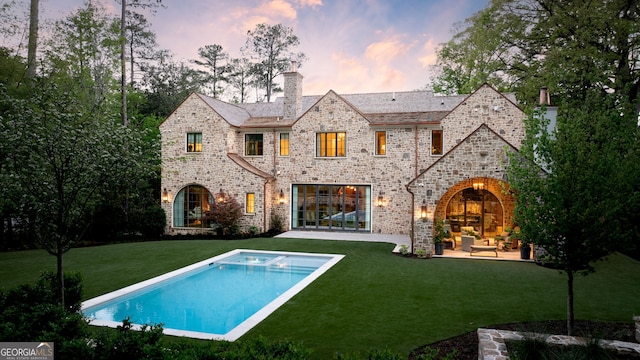 41 Blackland Rd NW, Atlanta, GA 30342 - back of property at dusk with a chimney, a patio area, a lawn, an outdoor hangout area, and an outdoor pool