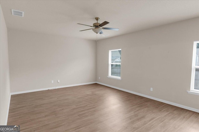 spare room with visible vents, baseboards, light wood-style floors, and a ceiling fan