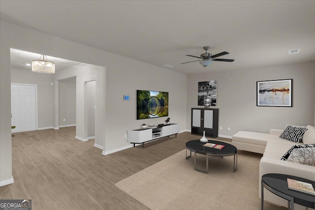 living room with ceiling fan with notable chandelier, wood finished floors, visible vents, and baseboards