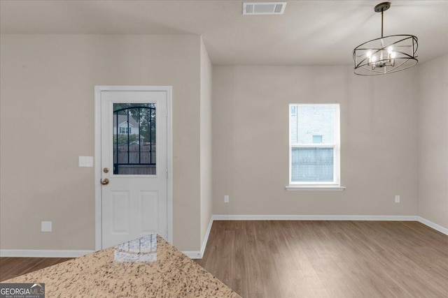 entryway with a notable chandelier, wood finished floors, visible vents, and baseboards