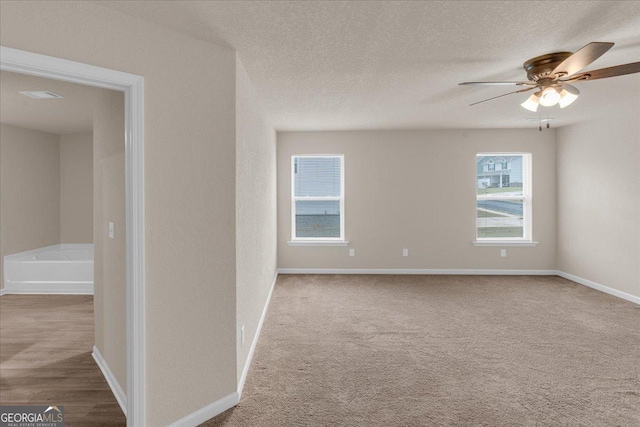 spare room featuring carpet, a ceiling fan, baseboards, and a textured ceiling