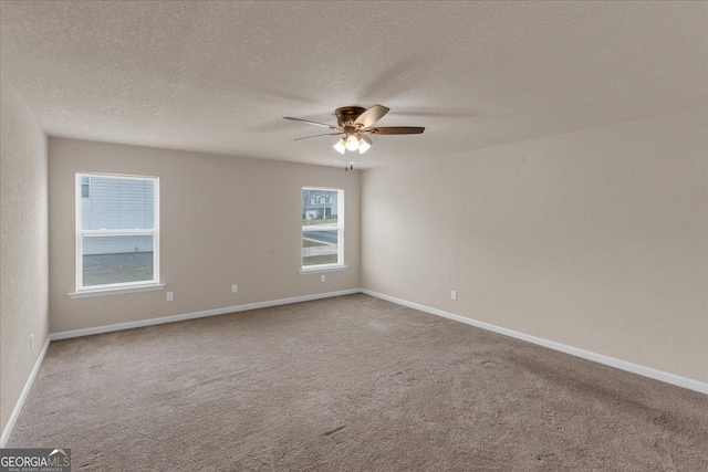 carpeted spare room featuring baseboards, a textured ceiling, and a ceiling fan