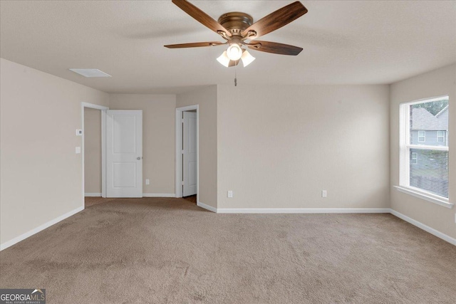 carpeted empty room featuring a textured ceiling, a ceiling fan, and baseboards