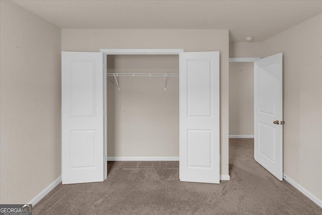 unfurnished bedroom featuring baseboards, carpet floors, and a closet