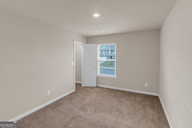 carpeted spare room featuring visible vents, baseboards, and a textured ceiling