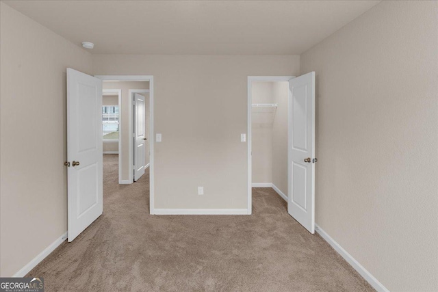 unfurnished bedroom with a spacious closet, baseboards, and carpet floors