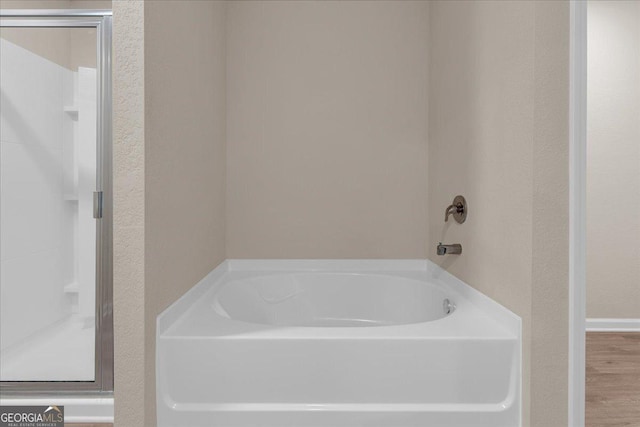 bathroom featuring a garden tub, wood finished floors, and a stall shower