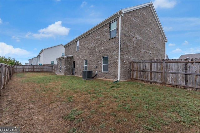 rear view of house featuring cooling unit, a lawn, brick siding, and a fenced backyard